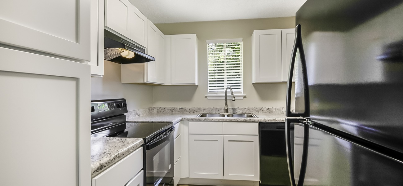 spacious and well lit kitchen with granite counter tops and stainless steel appliances 